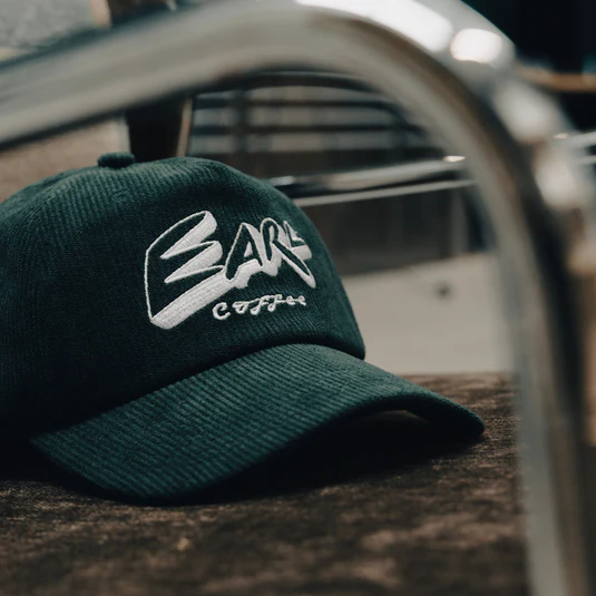 Dark green corduroy EARL Coffee cap on a workshop counter