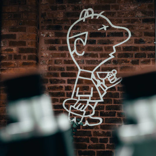 Hand-painted EARL Coffee mural of a character holding an espresso cup, on an exposed brick wall