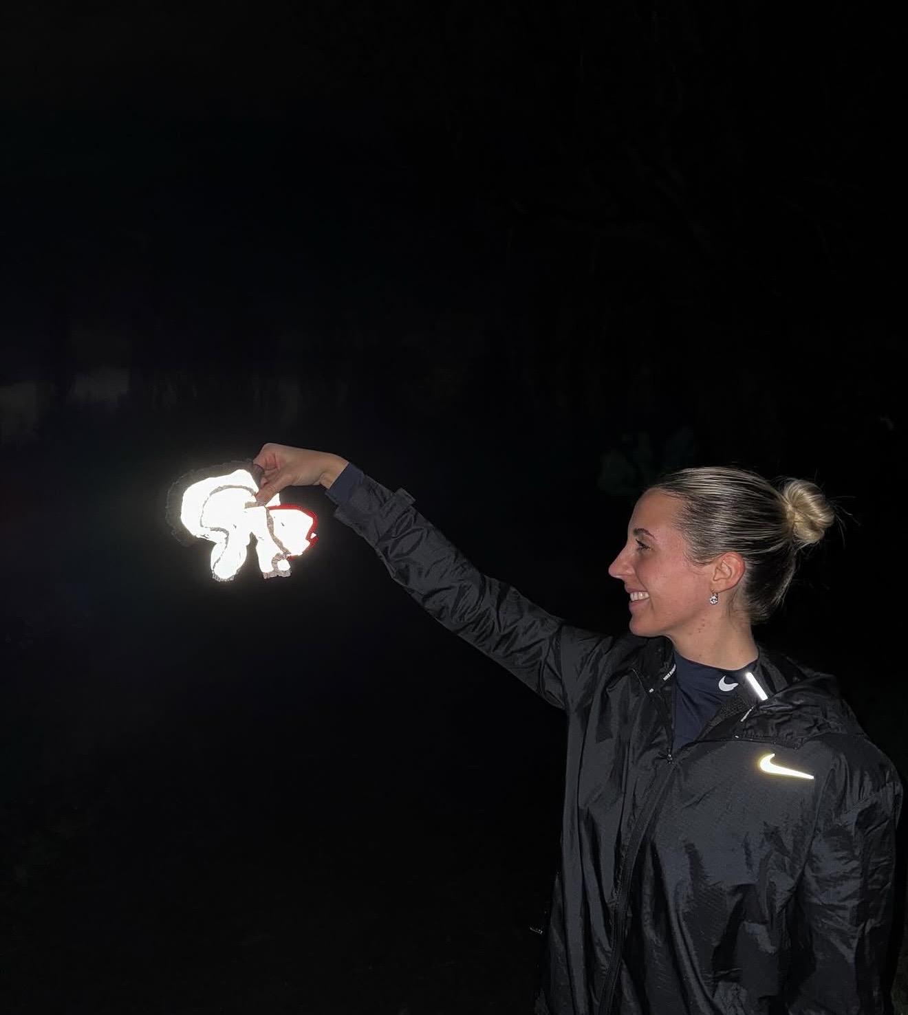 Eve, founder of Eve Marmalade, holding up a reflective scrunchie at night
